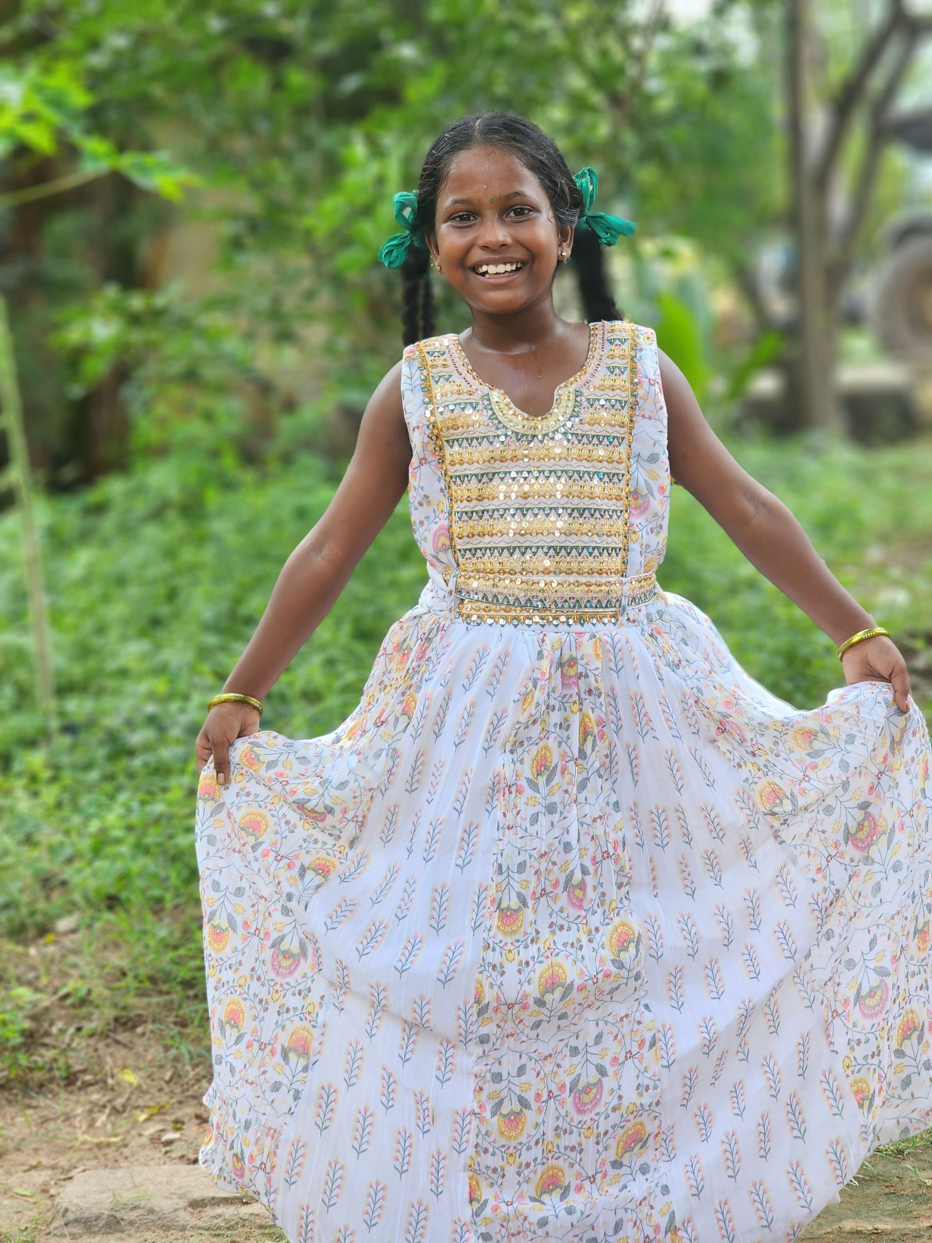 A little girl in a white dress is standing in a field.