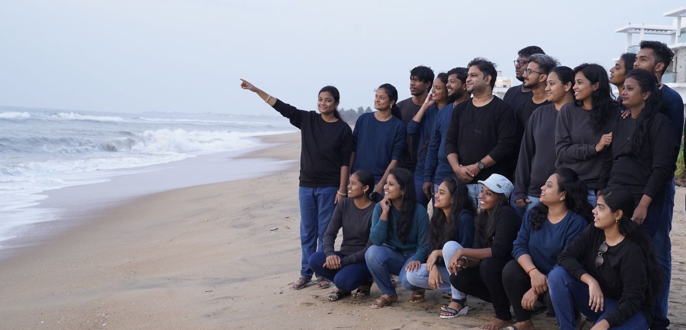 A group of people are posing for a picture on the beach.