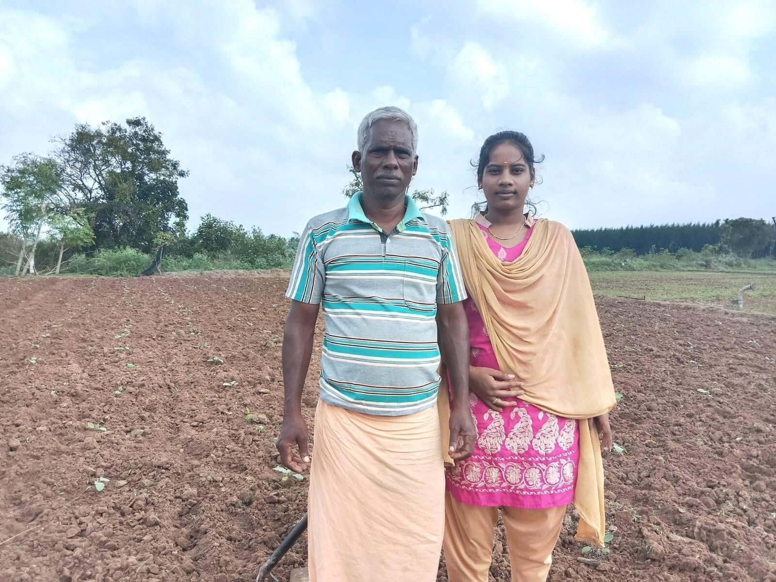 A man and a woman are standing next to each other in a field.