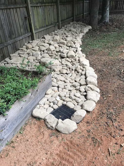 River rock drainage system installed along a residential fence line in Larchwood, Iowa