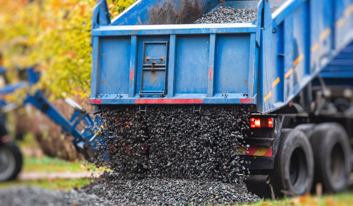 Gravel delivery truck unloading aggregate material for construction projects