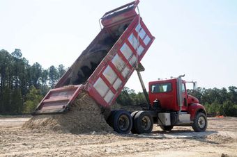 Dump truck delivering fill sand and aggregate material for site preparation in Larchwood, Iowa