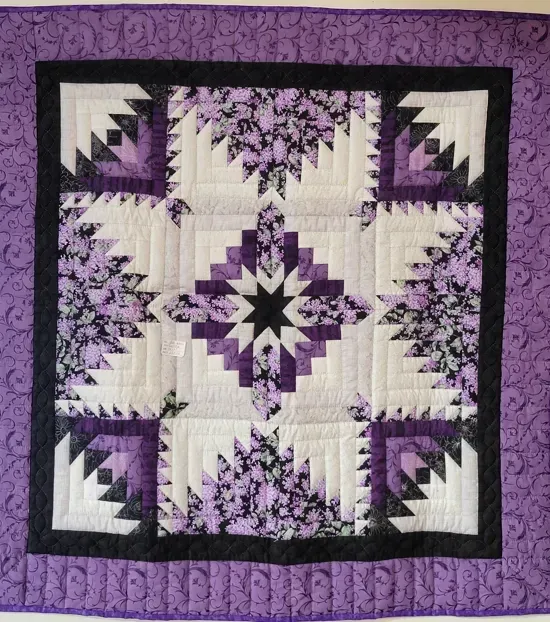 A purple and white quilt with a black border