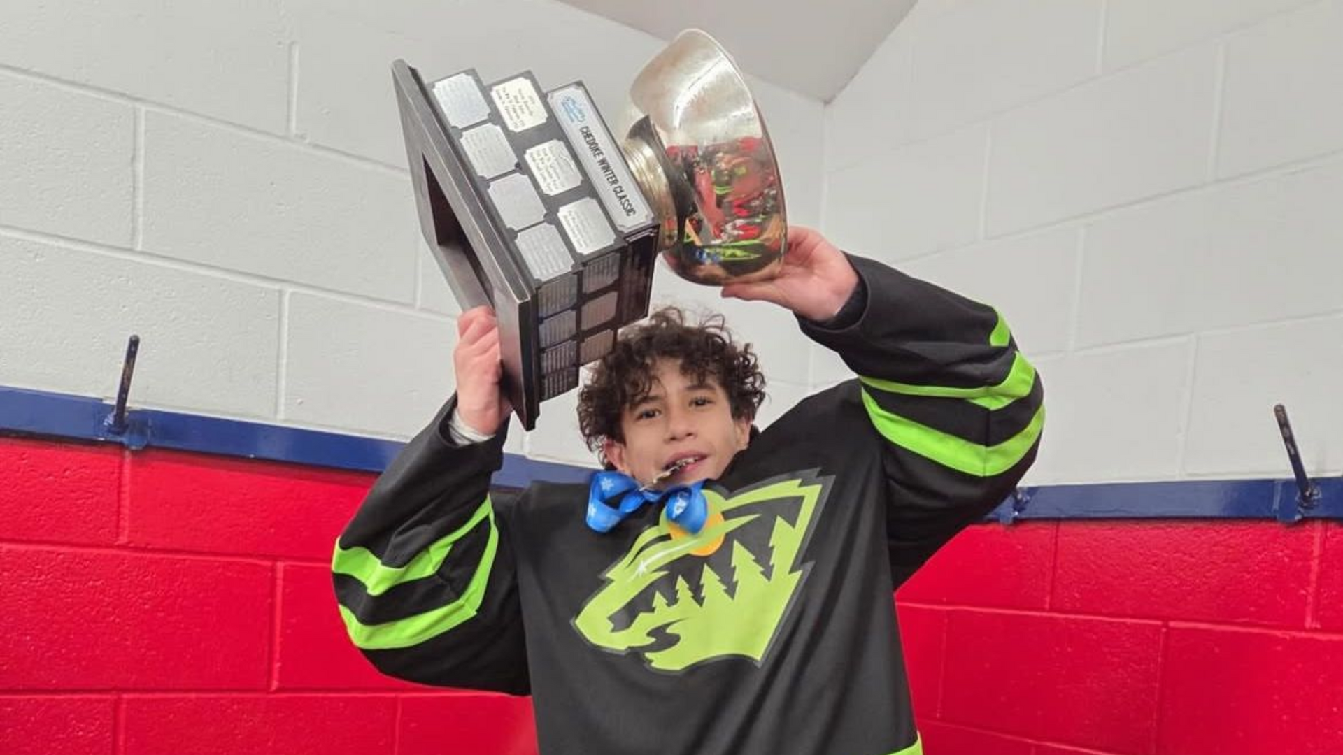 Person holding up a trophy and a tray of awards in a red-and-blue gymnasium
