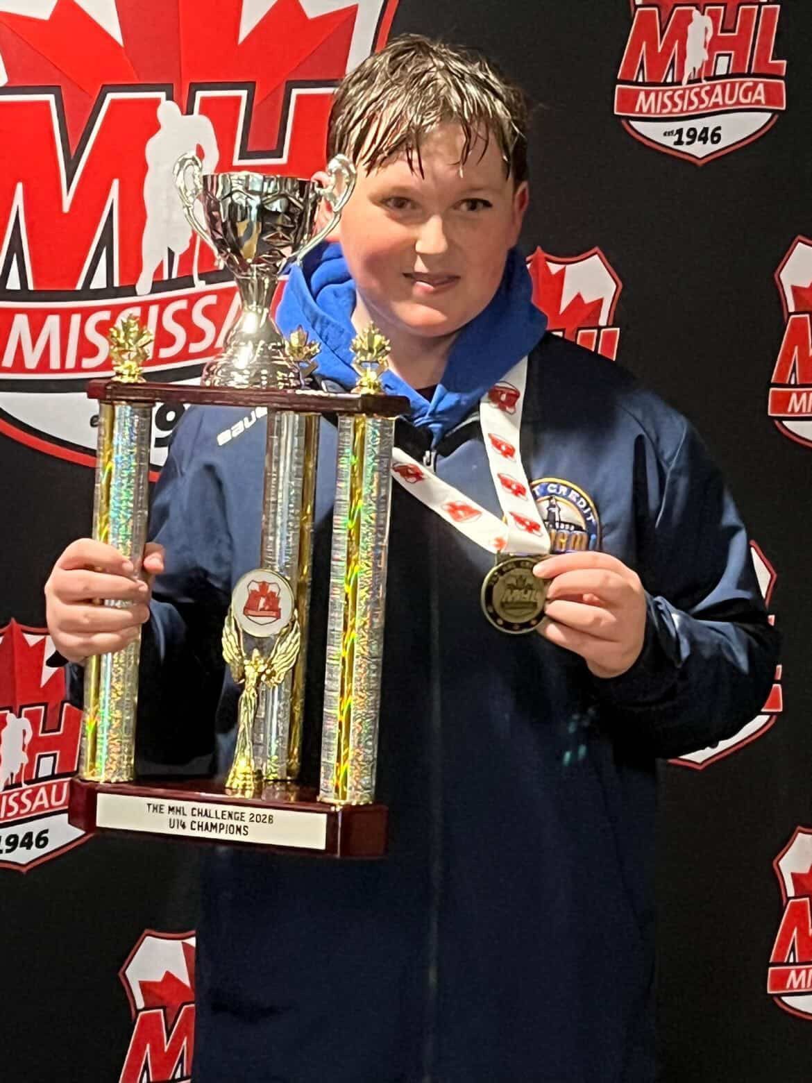 Person in a blue jacket holding a trophy in front of an NHL Mississippi backdrop.