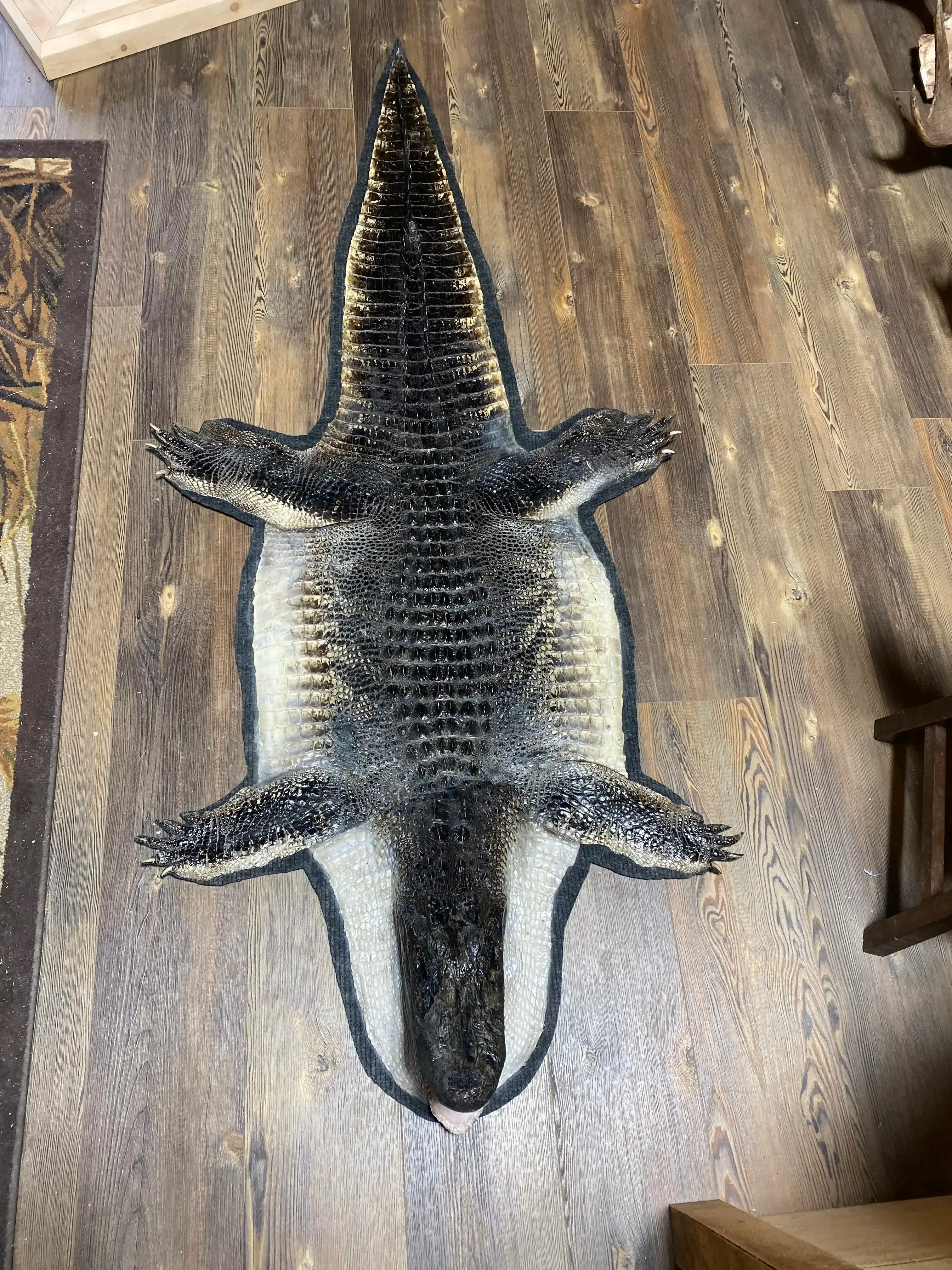 A rug with a picture of a crocodile on it is sitting on a wooden floor.