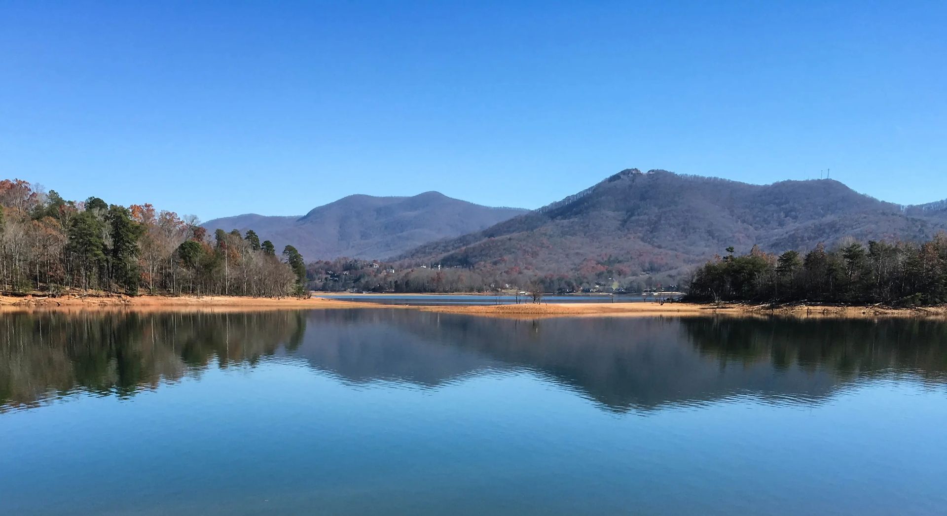 A lake with mountains in the background and trees on the shore.