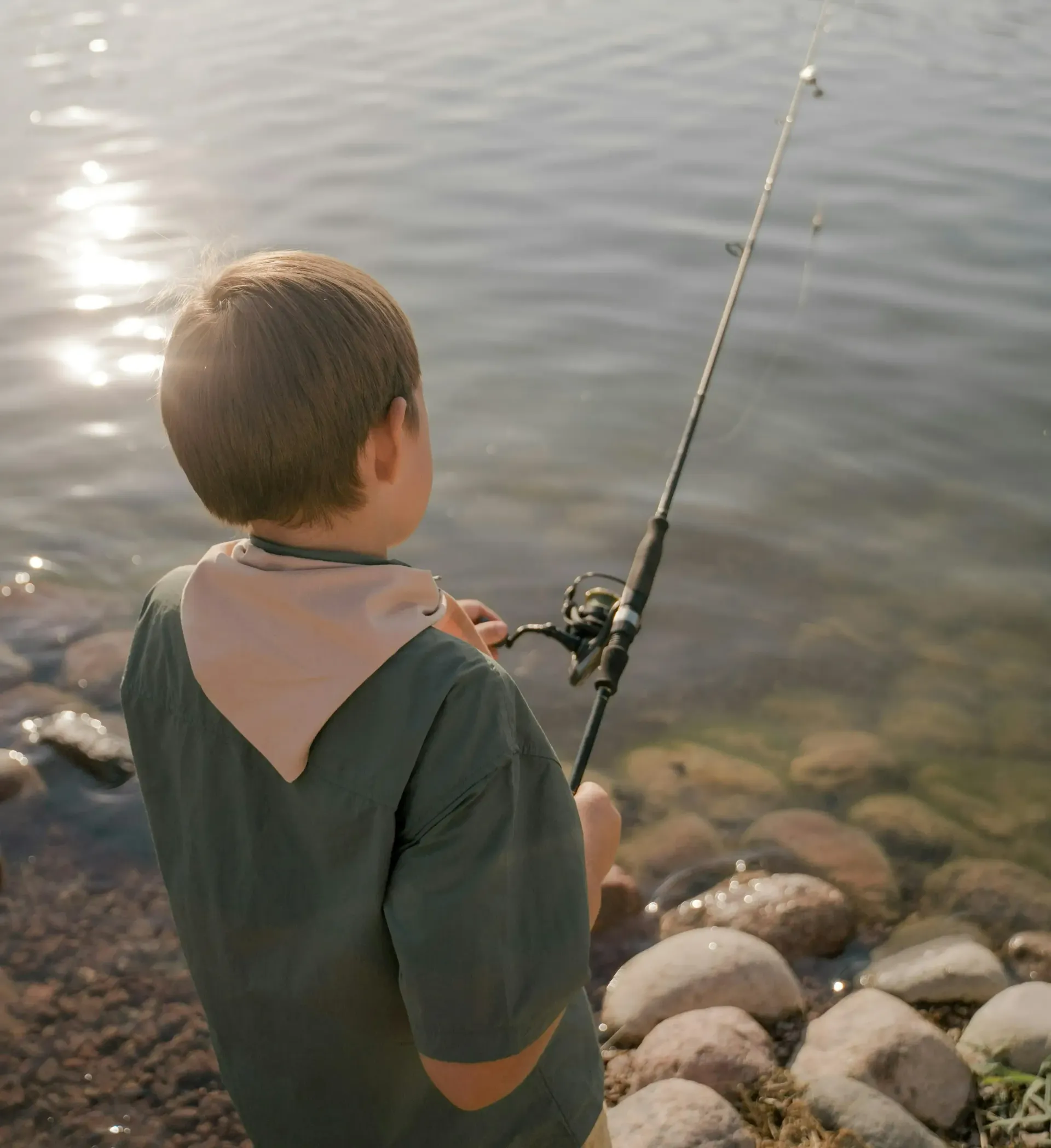 A young boy is fishing in the water with a fishing rod