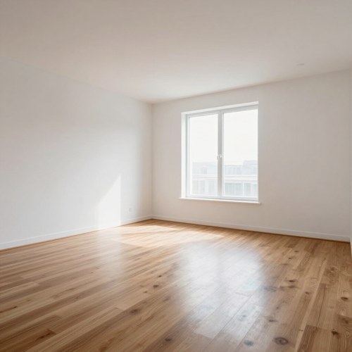 Empty bright room with white walls, wood floor, and a large sunlit window