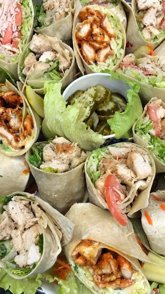 Assorted lettuce wraps with chicken, tomatoes, and sauces arranged on a platter, centered around a dipping cup