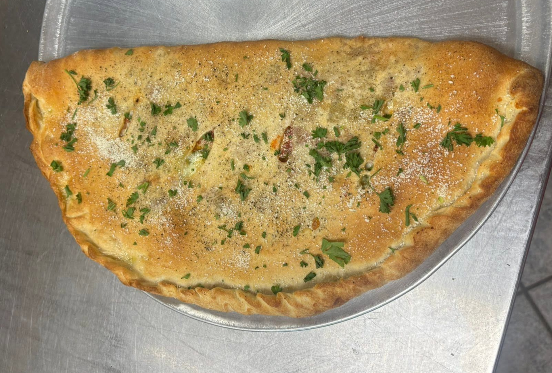 Golden-brown folded crepe with green herb garnish on a plate