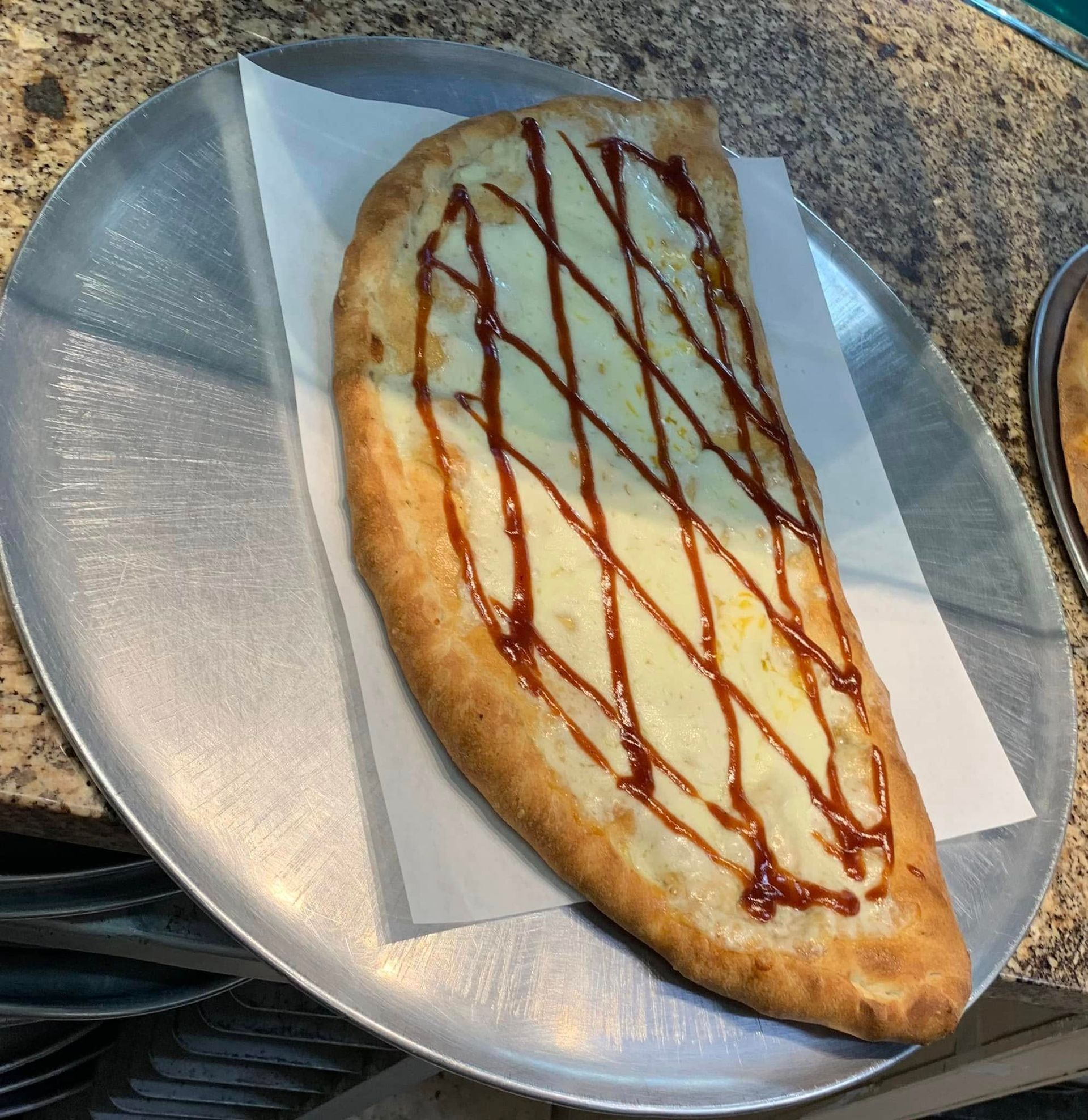 Chocolate-drizzled crescent pastry on a silver plate lined with parchment paper