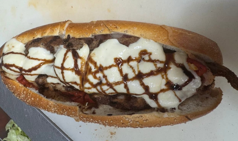 Open-faced sandwich with melted cheese and drizzled sauce on a toasted roll