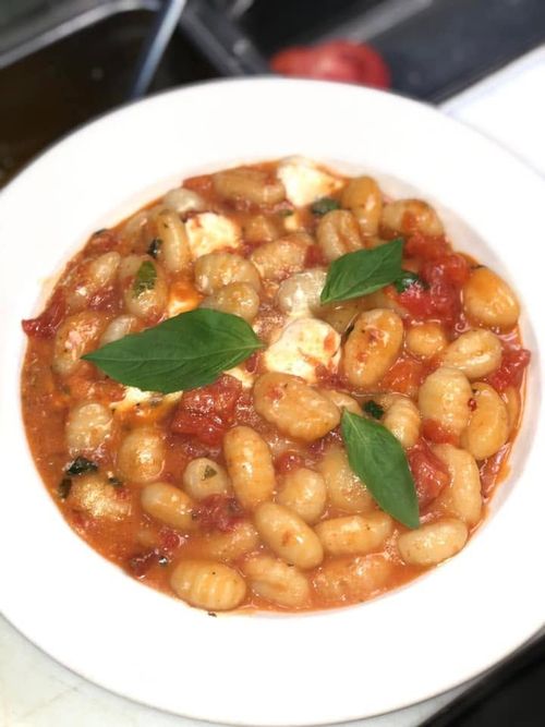 Bowl of gnocchi in red tomato sauce topped with basil leaves
