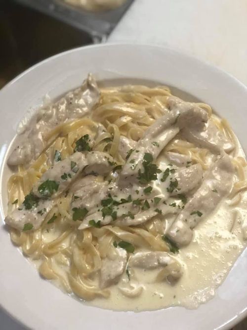 Creamy chicken pasta garnished with parsley in a white bowl