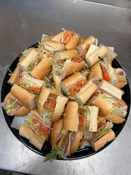 A plate piled with assorted sandwich pieces on a dark surface.