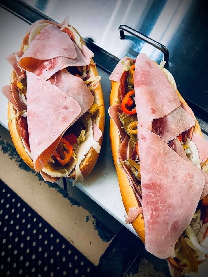 Two ham sandwiches on a tray, topped with folded slices of meat and mustard-colored filling