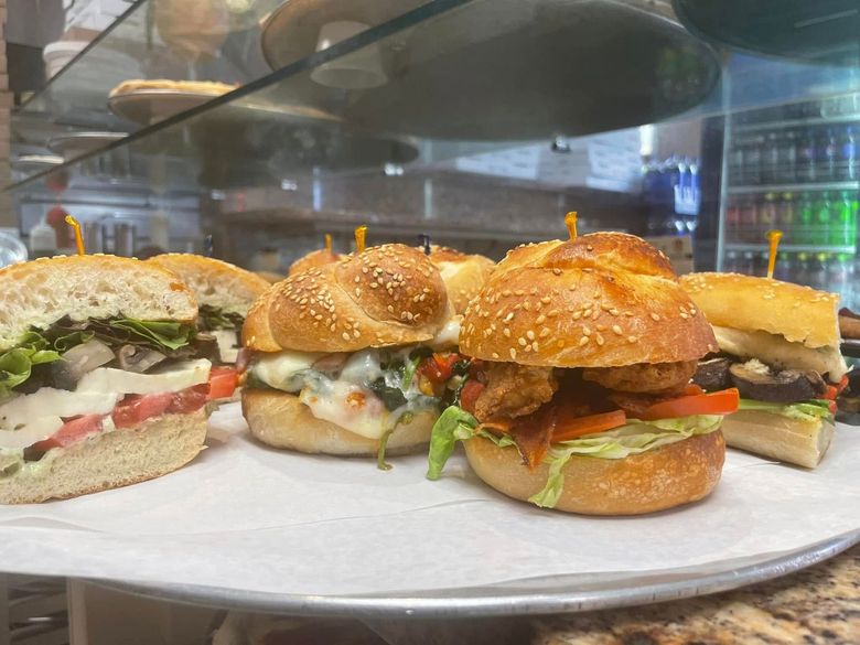 Assorted mini sandwiches on a plate behind a glass display case