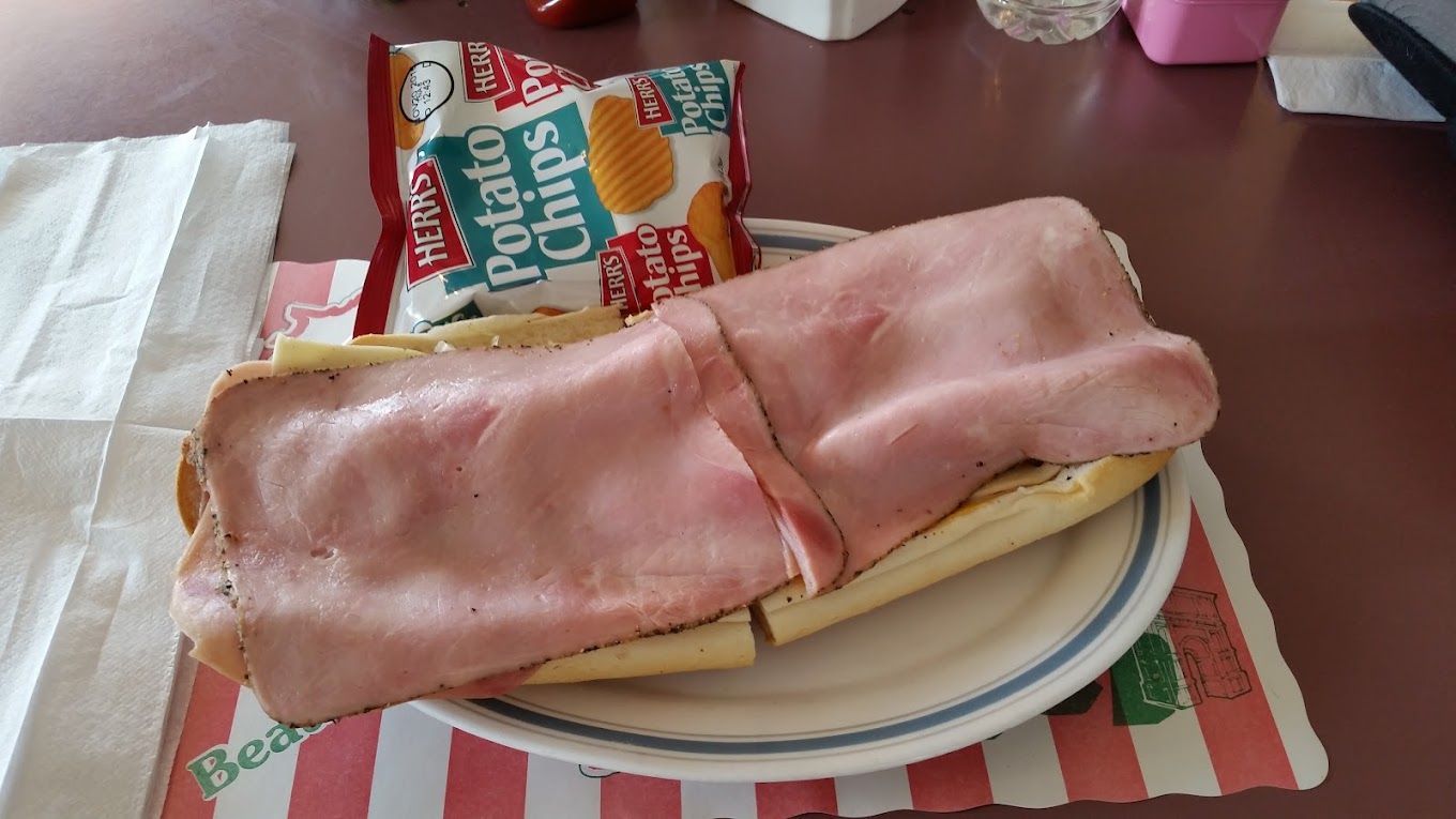 Ham and cheese sandwich on a plate with a snack bag in the background