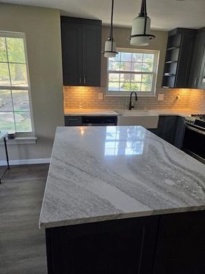 Modern kitchen with dark cabinets, marble island, pendant lights, and a window over the sink.