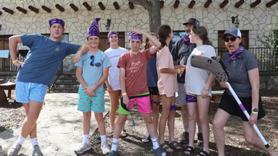 group of middle school aged children wearing purple bandanas and posing for the camera at a ranch