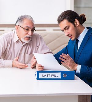 Two men are sitting at a table looking at a last will.