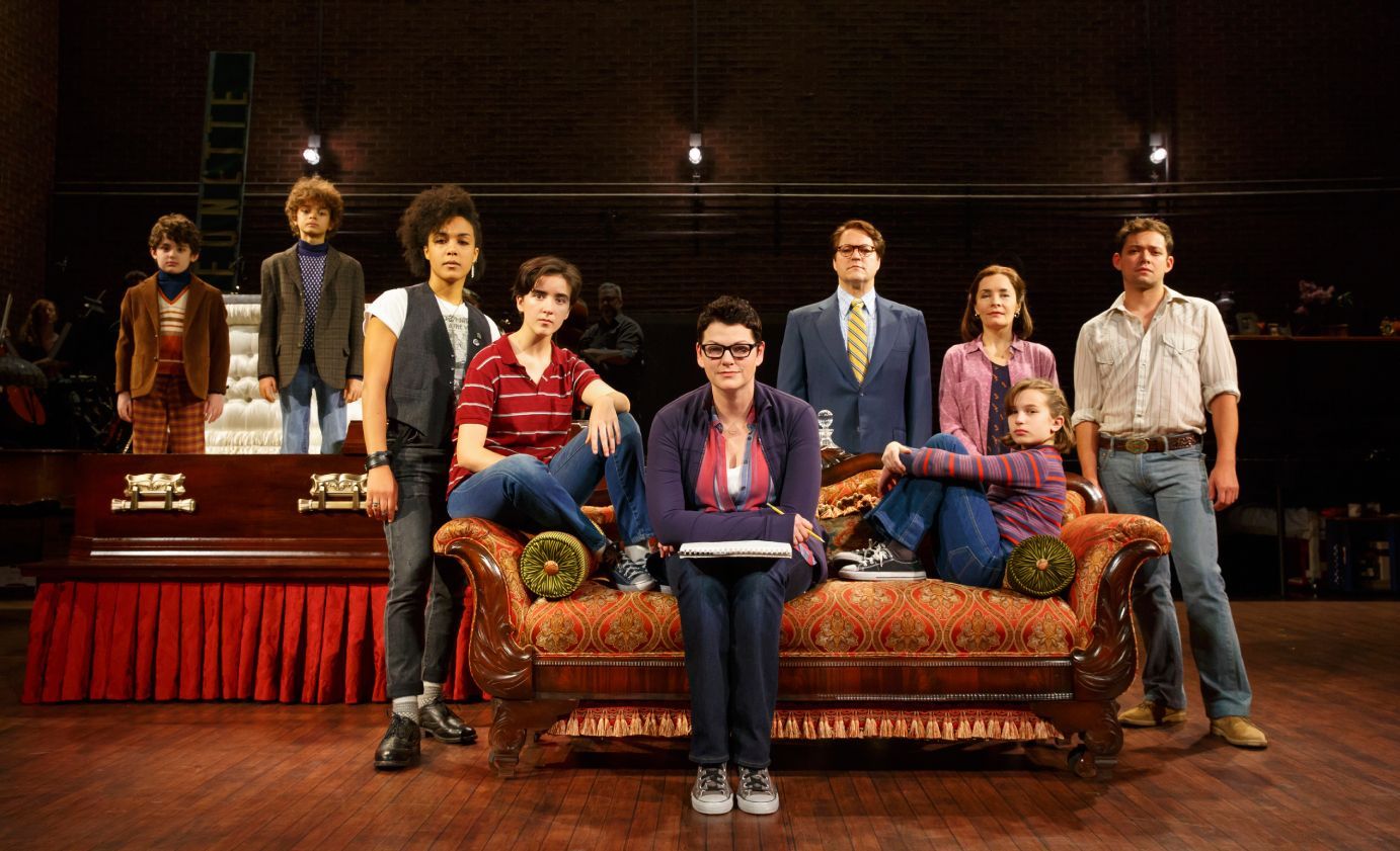 A group of people standing around a couch on a stage.