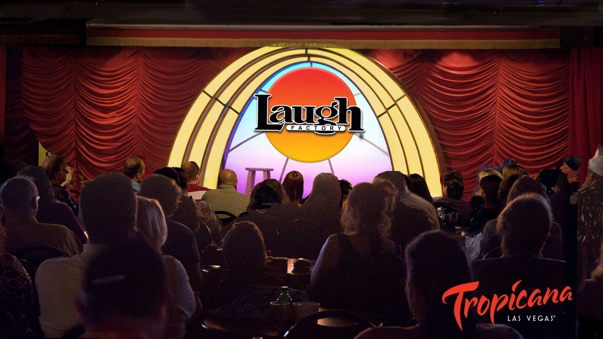 a crowd of people are sitting in front of a stage at the laugh comedy club