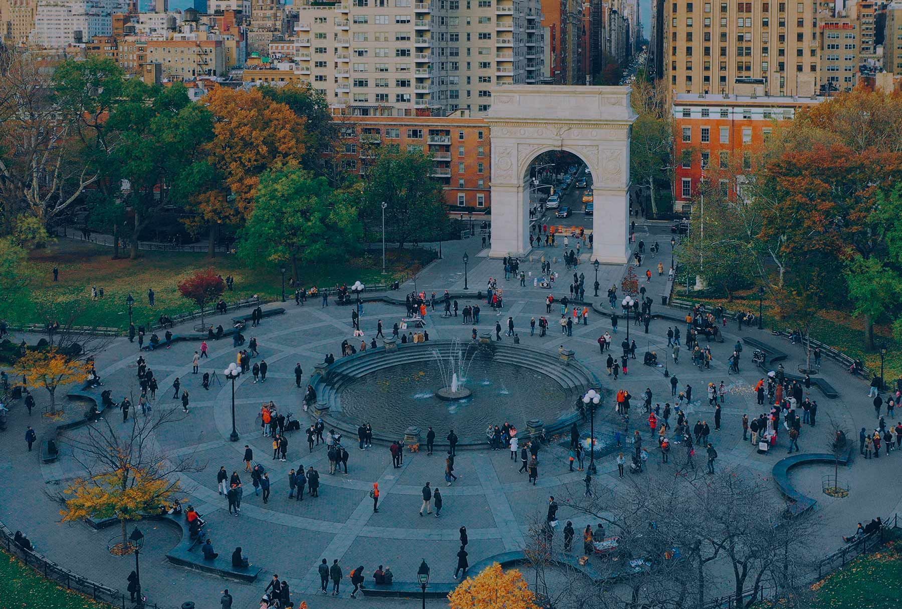 An aerial view of a city park with a fountain in the middle