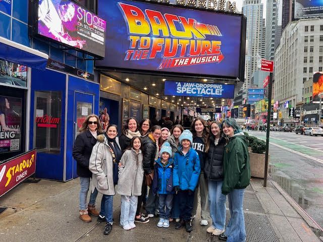 A group of people are standing in front of a back to the future musical sign.