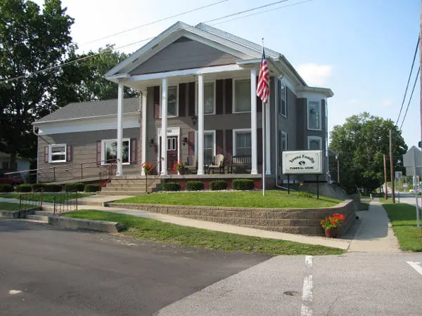 Gray building with white columns and sign; wheelchair accessible ramp.