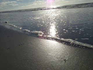 The sun is reflected in the water on the beach.