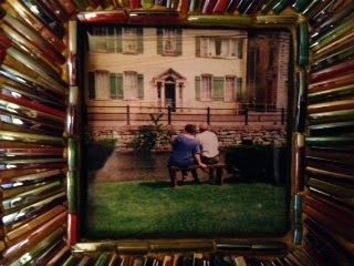 A picture of two people sitting on a bench in front of a house