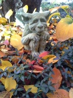 A statue of a gargoyle sitting in a pile of leaves