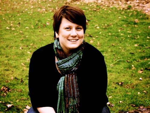 A woman wearing a scarf and a black shirt is sitting in the grass