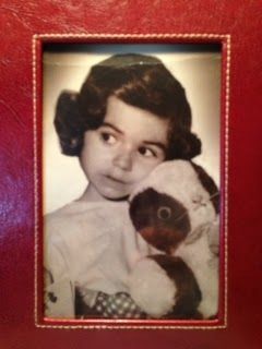 A black and white photo of a little girl holding a stuffed animal
