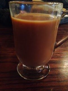 A cup of coffee is sitting on a wooden table.