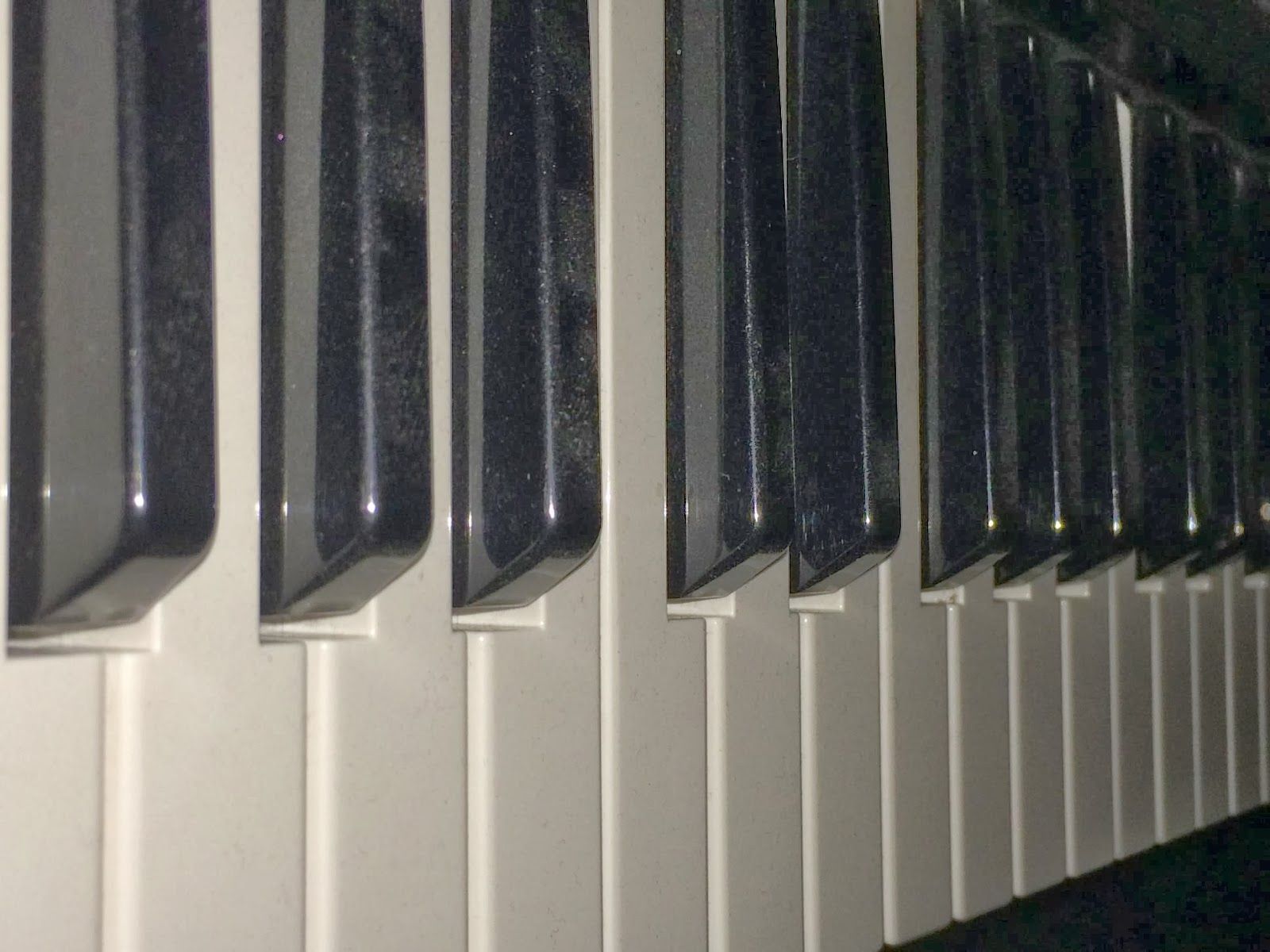 A close up of a piano keyboard with black and white keys