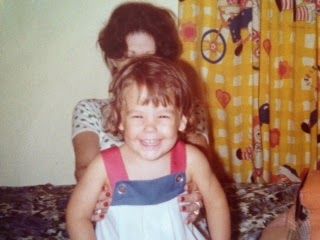 A little girl is being held by a woman and smiling