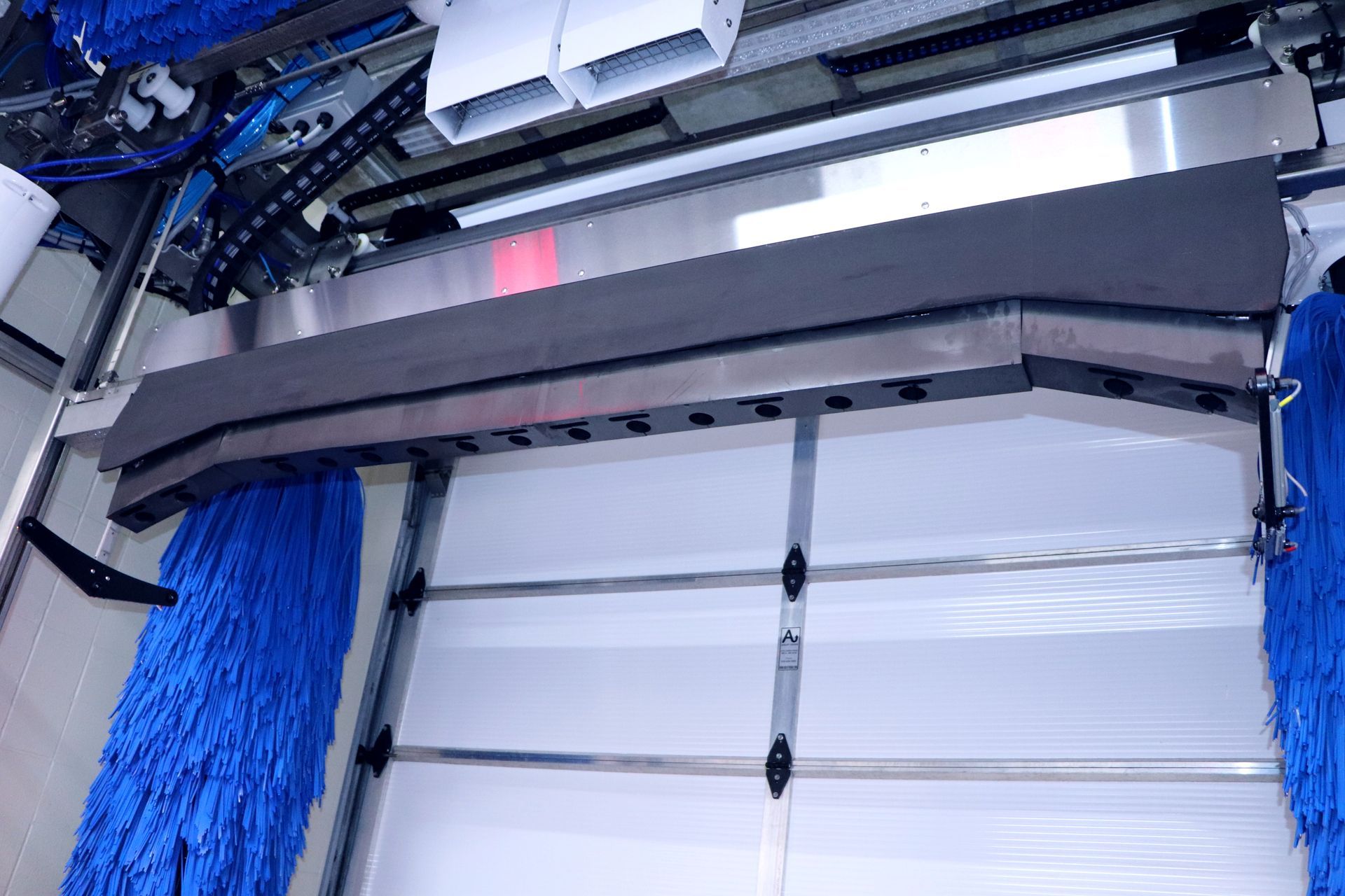 Inside car wash. Blue brushes, gray overhead bar.