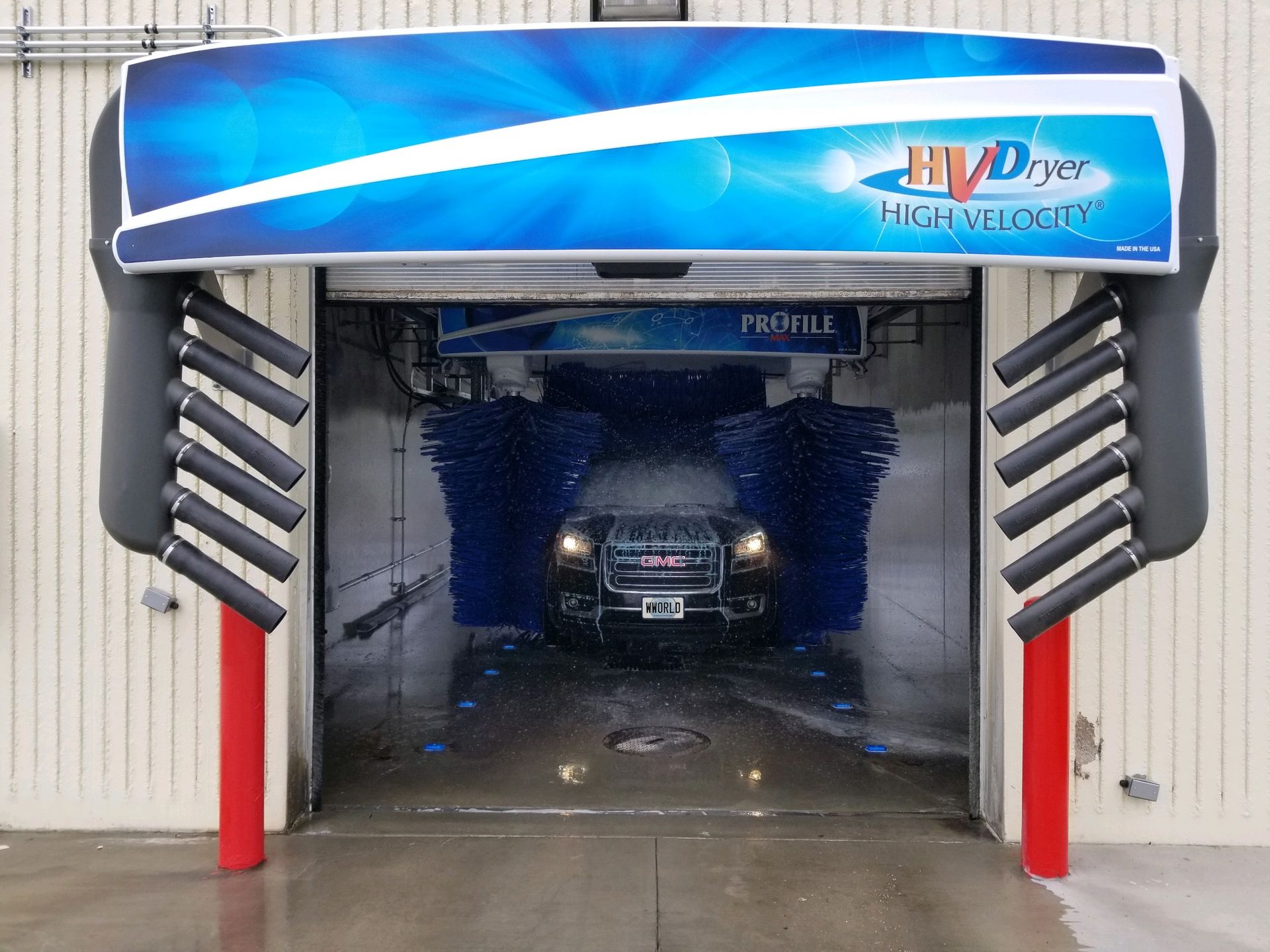 Car driving through a Profile in bay car wash bay with a high velocity dryer on the outside of the building.