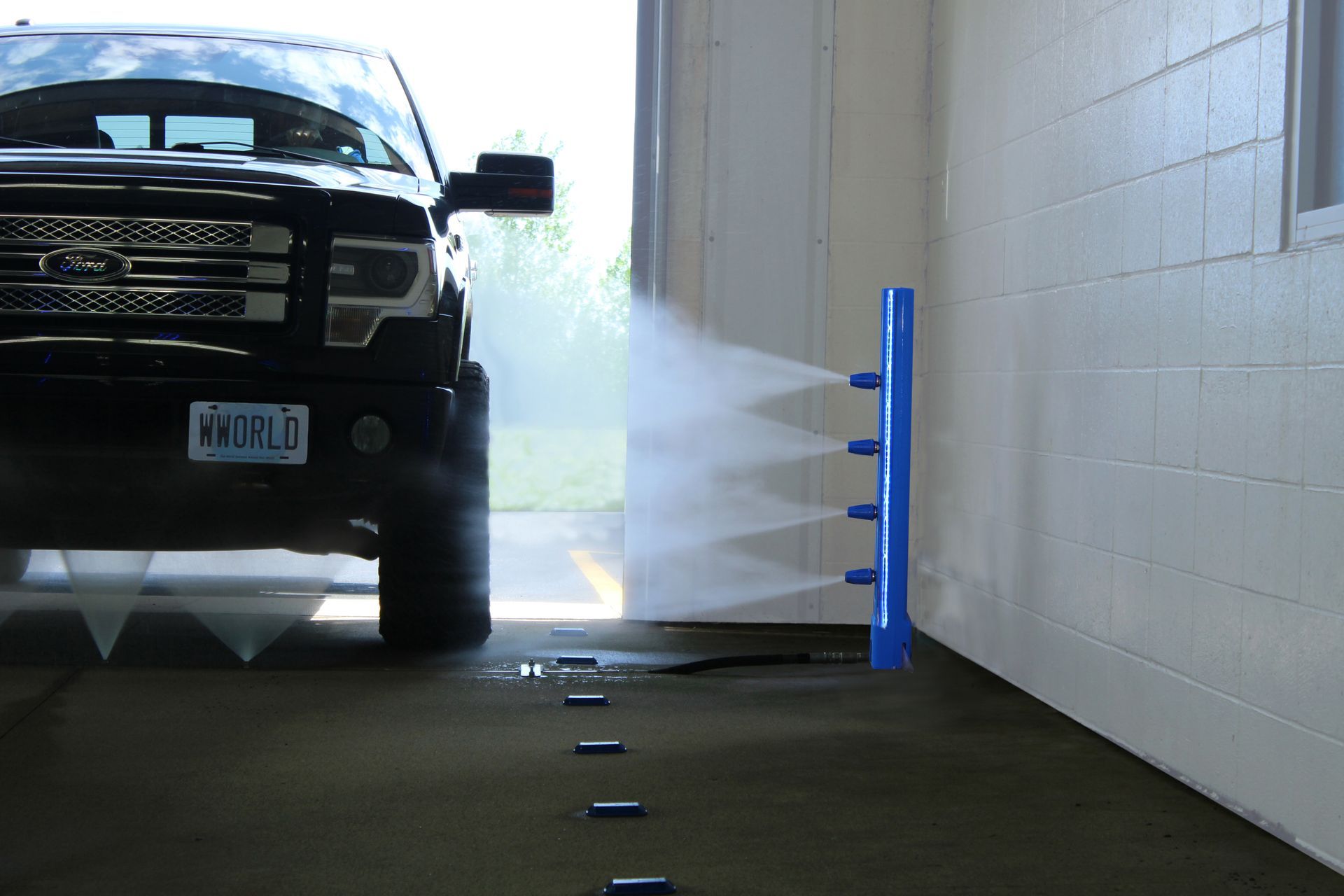 Black truck entering a car wash, spraying from the Power Tower.