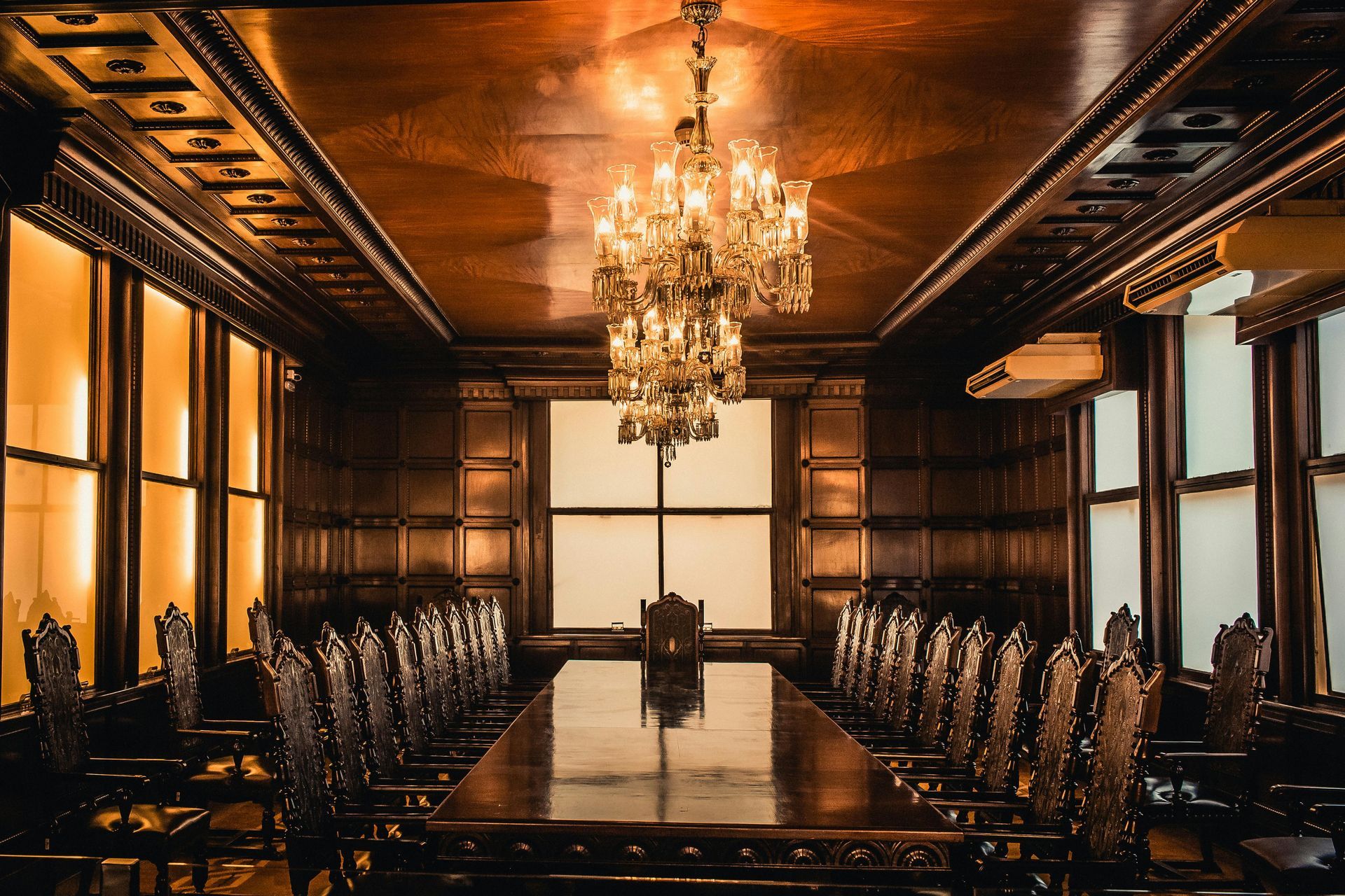 A large room with a long table and chairs and a chandelier hanging from the ceiling.