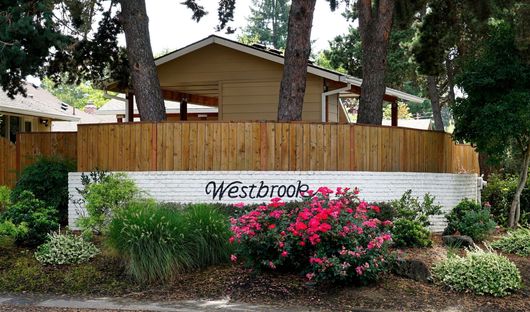 A house with a wooden fence and a sign that says Westbrook