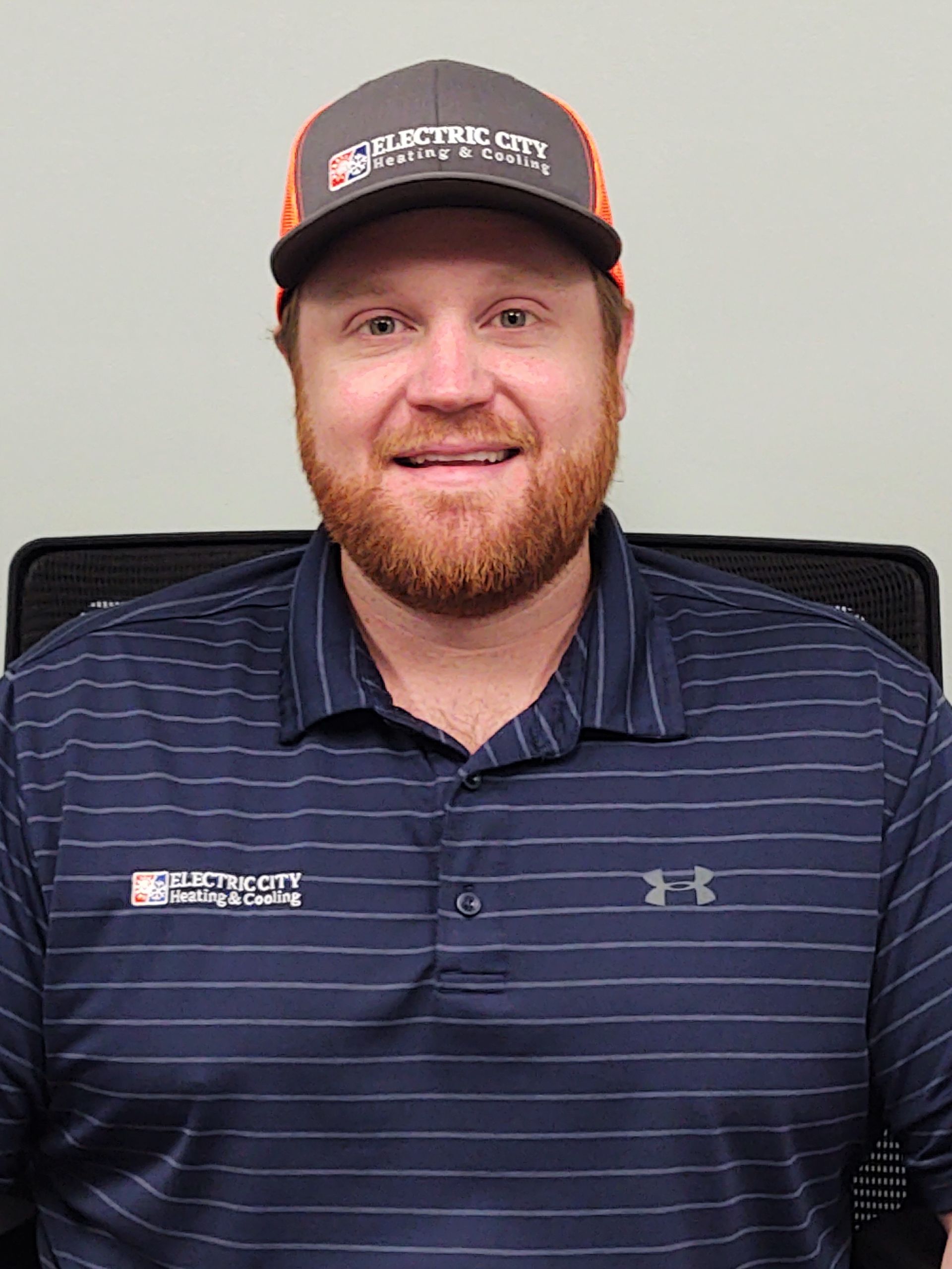 A man with a beard is wearing a hat and a striped shirt.