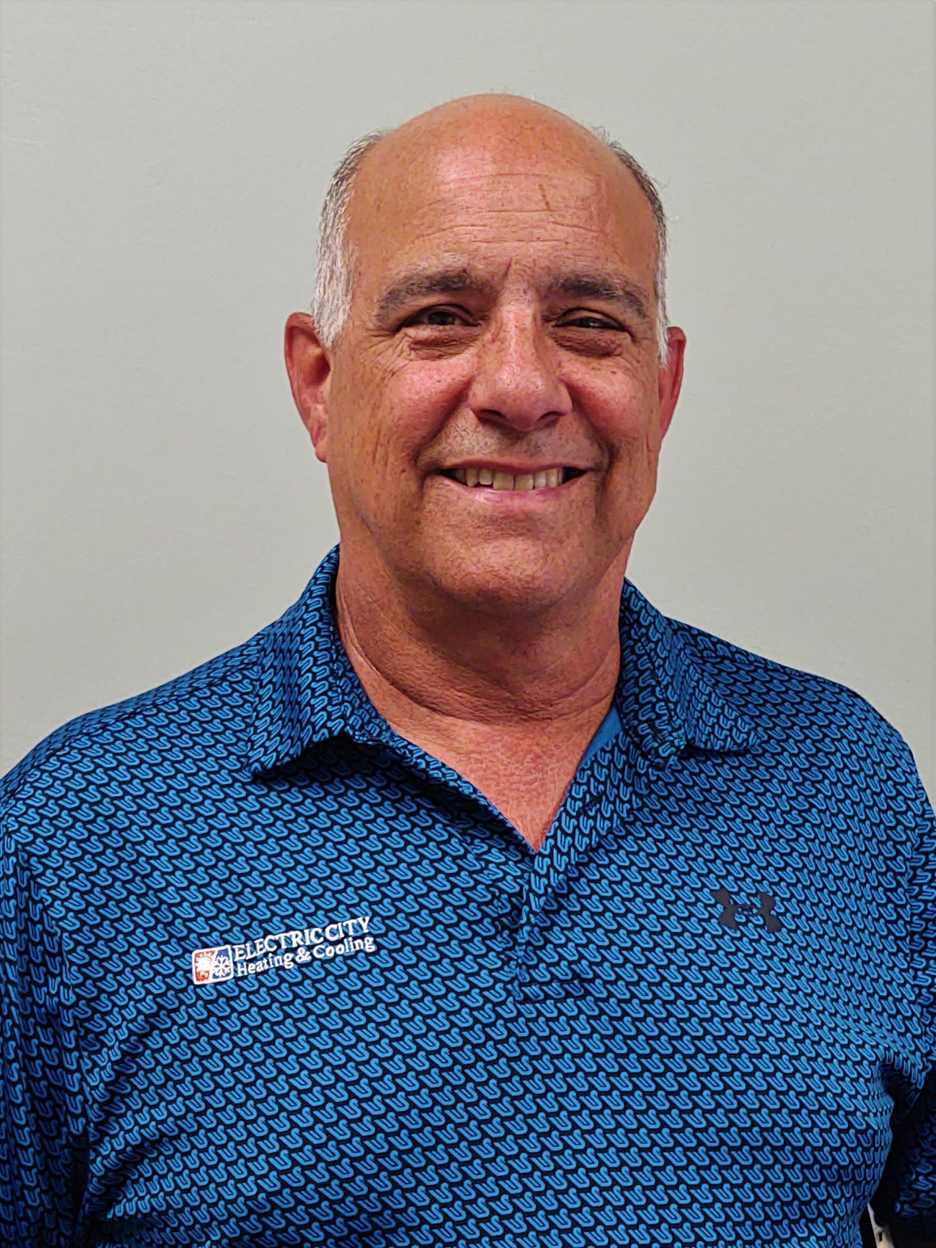 A bald man wearing a blue shirt is smiling for the camera.