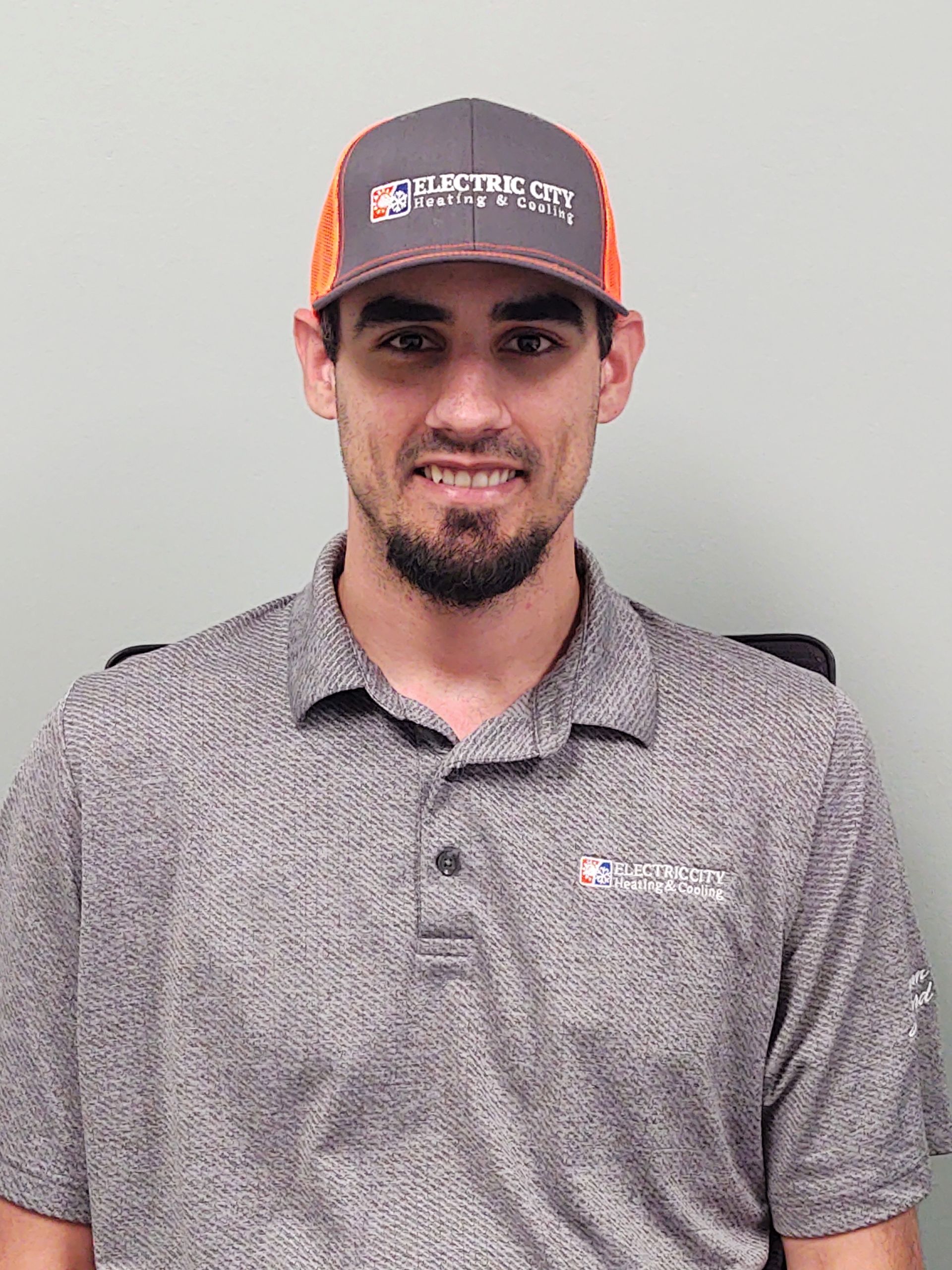 A man wearing a hat and a polo shirt is smiling for the camera.