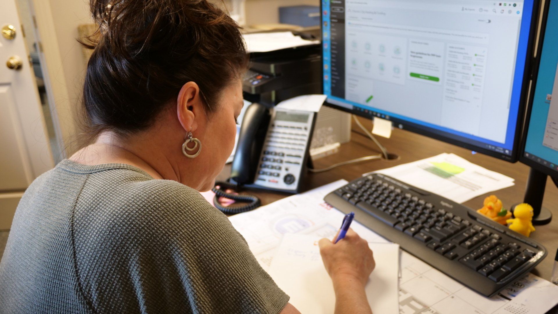 A woman is sitting at a desk in front of a computer.