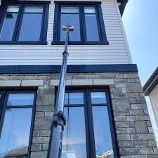 Exterior of a two-story house with blue trim, stone lower facade, and a pole with lights in front