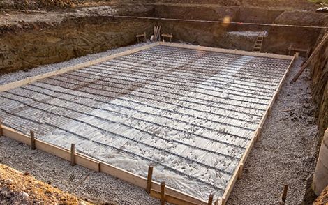 Concrete foundation slab with rebar grid and wooden formwork at a construction site